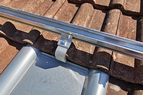 Aluminiumschiene mit Halteklemme über einem Blechziegel