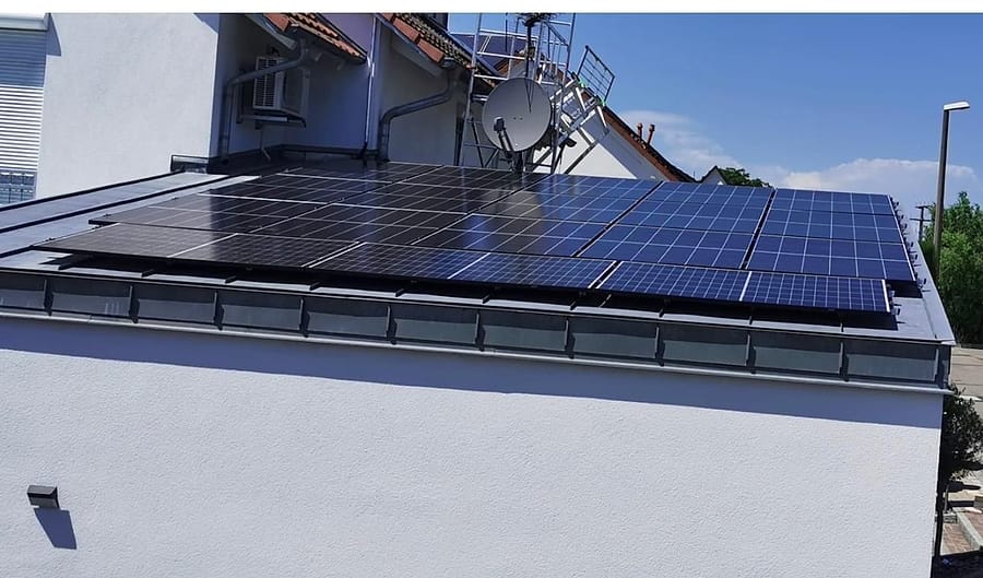 Flach geneigtes Dach mit schwarzen Photovoltaikmodulen neben älteren blauen Modulen