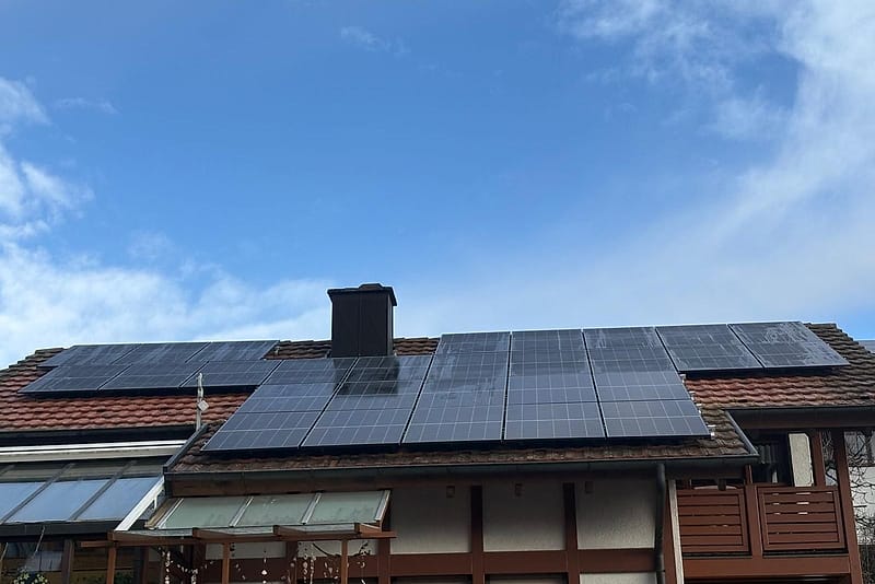 Wohnhaus mit rotem Ziegeldach, belegt mit Photovoltaikmodulen auf zwei versetzten Dachflächen